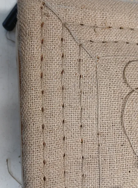 Toile de jute piquée à la main sur un siège en cours de garnissage traditionnel