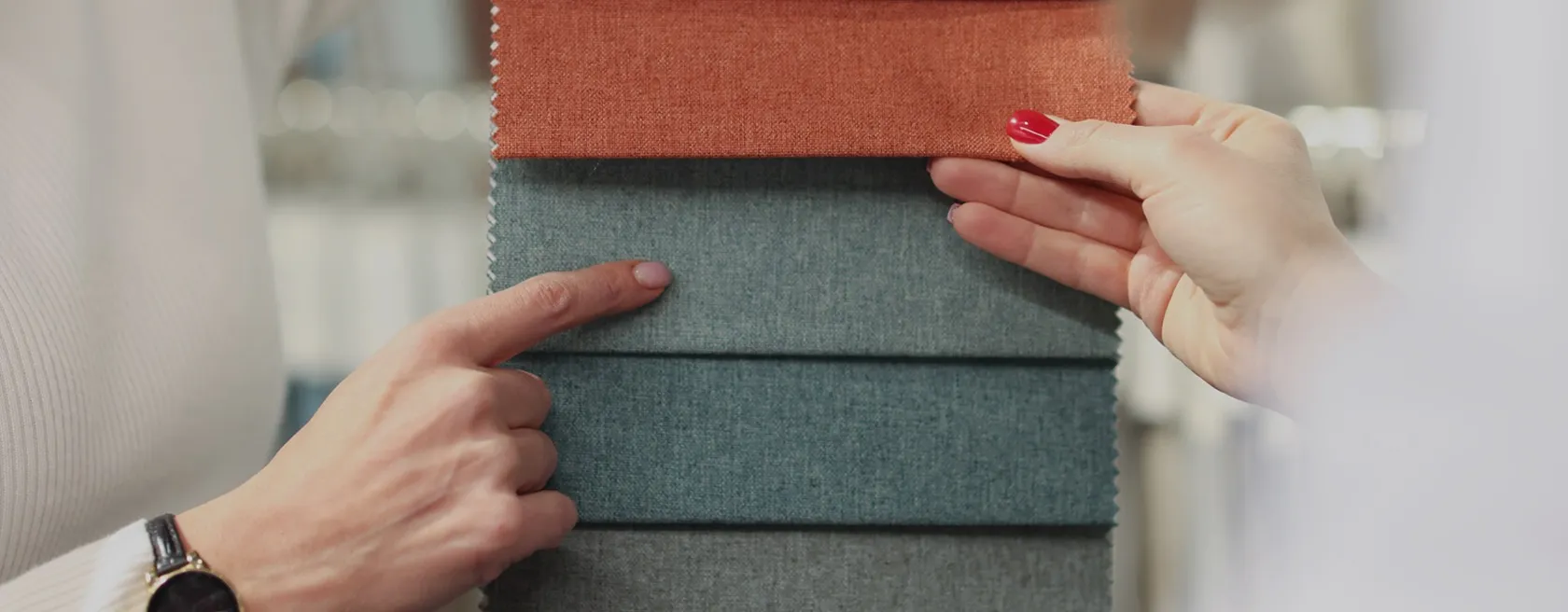 Mains choisissant des échantillons de tissus d’ameublement gris et orange